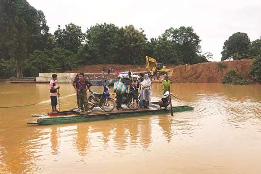 People use a makeshift ferry to cross the swollen Xe Khong river due to flash flooding in Sanamxai, Attapeu province.