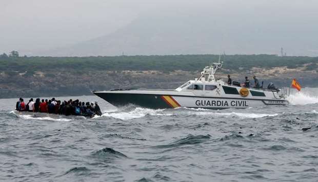 Spanish civil guards try to stop migrants before disembarking from a dinghy at ,Del Canuelo, beach after they crossed the Strait of Gibraltar sailing from the coast of Morocco, in Tarifa, sourthern Spain.