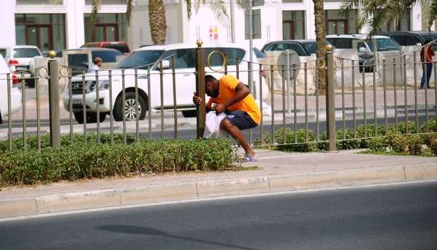 A person 'squeezing' through a gap along the median fence on Grand Hamad Street