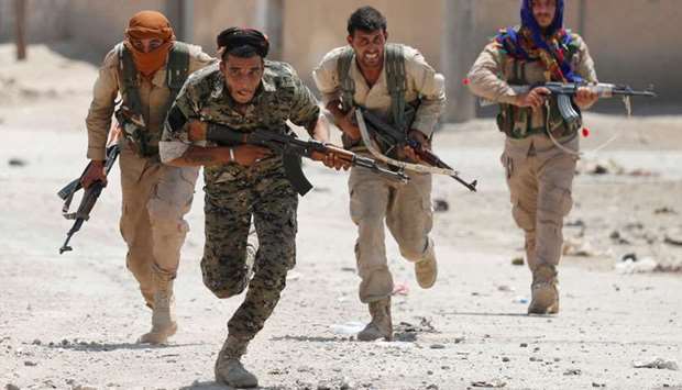 Kurdish fighters from the People's Protection Units (YPG) run across a street in Raqqa