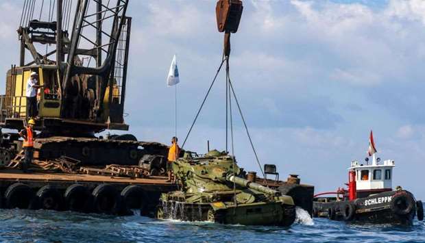 Environmental activists drop off an old battle tank provided by the Lebanese Armed Forces into the Mediterranean Sea