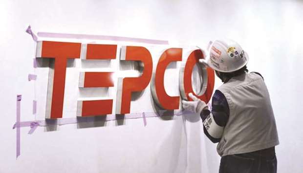 A worker puts up new logo of Tokyo Electric Power Company on a wall in Tokyo. Japanu2019s biggest electricity provider and the operator of the wrecked Fukushima nuclear plant, has run oil, coal and gas plants at rates higher than their typical maximum capacity, a spokesman said.