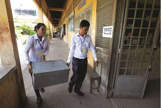 Election workers carry voting materials into a classroom to set up a polling booth at a school in Phnom Penh yesterday.