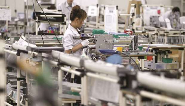 Employees work at an assembly line at a factory of Glory, a manufacturer of automatic change dispensers, in Kazo, north of Tokyo. Japanu2019s industrial production was seen down 0.4% in June from the previous month after it fell 0.2% in May, a poll of 16 economists found.