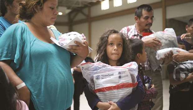 An eight-year-old girl from Honduras holds a Homeland Security bag as her family is released from detention with other undocumented immigrants at a bus depot in McAllen, Texas.