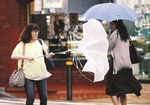 Passersby using umbrellas struggle against a heavy rain and wind as Typhoon Jongdari approaches Japanu2019s mainland in Tokyo yesterday.
