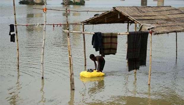 An Indian boy moves his belongings after flooding on the banks of the Ganges River in Allahabad on Saturday.