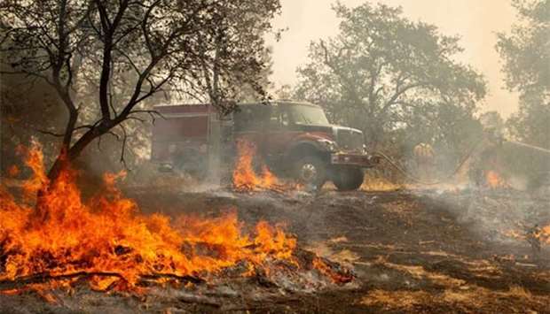 Firefighters douse a hotspot near homes as the Carr fire continues to burn near Redding, California, on Saturday.