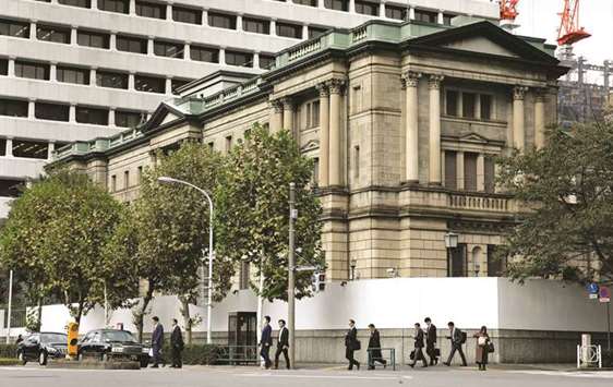 Pedestrians cross a road in front of the Bank of Japan headquarters in Tokyo. The BoJ is likely to cut bond purchases more drastically and more flexibly, which targets the super-long sector, to revive market liquidity and volatility.