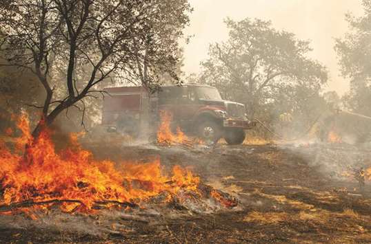 Firefighters douse a hotspot near various homes as the Carr Fire continues to burn near Redding, California.