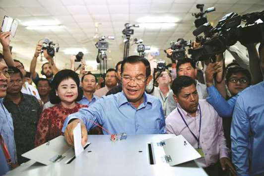 Cambodiau2019s Prime Minister Hun Sen (centre) casts his vote during the general elections as his wife Bun Rany (centre, left) looks on in Phnom Penh yesterday.