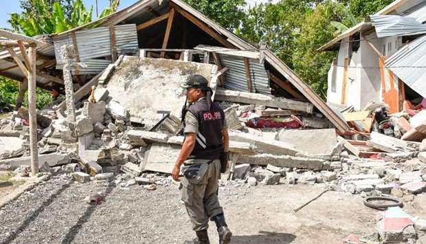 An Indonesian village security officer examines the remains of houses, after a 6.4 magnitude earthquake struck, in Lombok