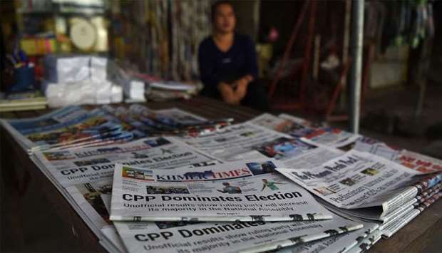 A vendor waits for customers with newspapers featuring reports on Prime Minister Hun Sen's ruling Cambodian Peoples Party (CPP) victory