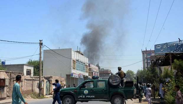 Afghan security personnel secure a road as smoke billows from the site of suicide attack as an ongoing attack between Afghan security force and suicide attackers in Jalalabad