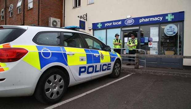 Police officers are seen standing guard outside a local pharmacy in Amesbury, nine miles north of Salisbury, southern England, on July 4, 2018 where two people were found unconcious at a residence in Amesbury
