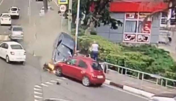 An image grab from a street camera footage that shows a car (black) hitting another car (red) after leaving a pavement it entered seconds before.