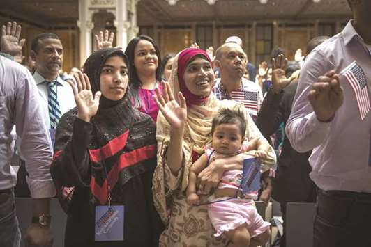 New US citizen Mosammat Rasheda Akter, from Bangladesh, holds her 7-month-old daughter Fahmida as she recites the Oath of Allegiance during naturalisation ceremony at the New York Public Library on Tuesday.