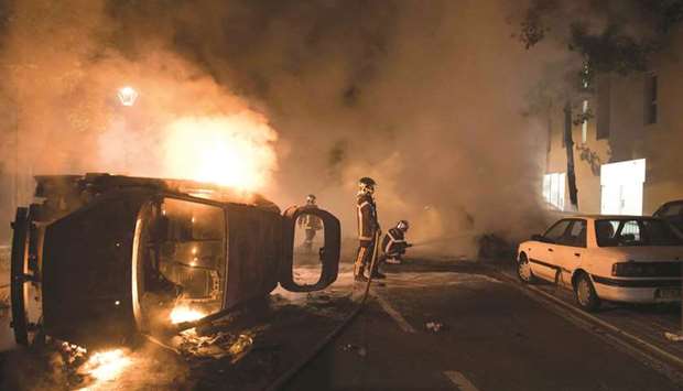 Firefighters work to put out a fire near a burning car in the Malakoff neighbourhood of Nantes late on Tuesday.