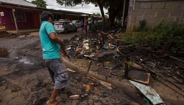 A man throws burnt debris from the house of opposition student leader Yubrank Suazo which was burnt down amid the ongoing conflict in Nicaragua, into a pile in a corner in the town of Masaya, about 35 km from Managua.