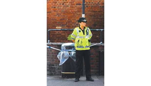 A police officer stands guard over a public rubbish bin that is cordoned off in Amesbury, near Salisbury, yesterday.