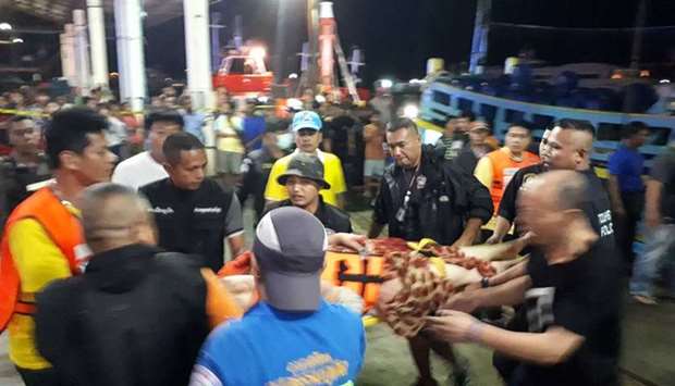 Thai rescue and paramedic personnel attend to rescued passengers of capsized tourist boat in rough seas at a port in Phuket yesterday.