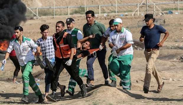 Palestinian paramedics carry a wounded person away from the scene of clashes with Israeli forces