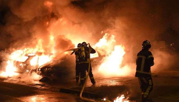 Firefighters work to put out a fire as cars burn in the Le Breil neighborhood of Nantes. A French policeman who shot dead a young black man in western France earlier this week, sparking four nights of rioting.