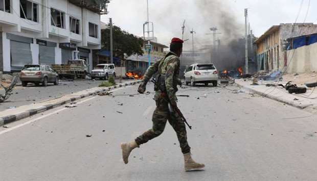 A Somali military officer runs to secure the scene of a suicide car bombing near Somalia's presidential palace in Mogadishu