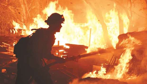 Firefighters battle a fast-moving wildfire that destroyed homes, driven by strong wind and high temperatures forcing thousands of residents to evacuate in Goleta, California.