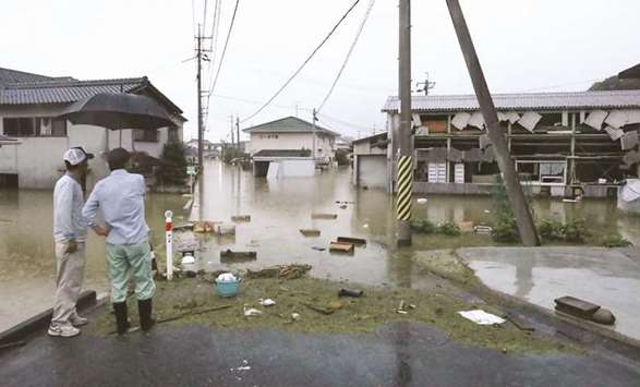 This picture shows officials looking at flooded houses in Kurashiki, Okayama prefecture, yesterday.