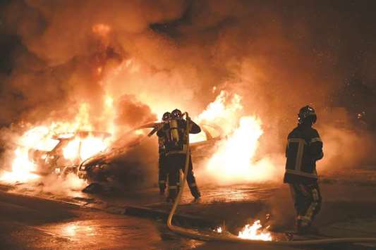 Firefighters work to put out a fire as cars burn in the Le Breil neighbourhood of Nantes early yesterday.