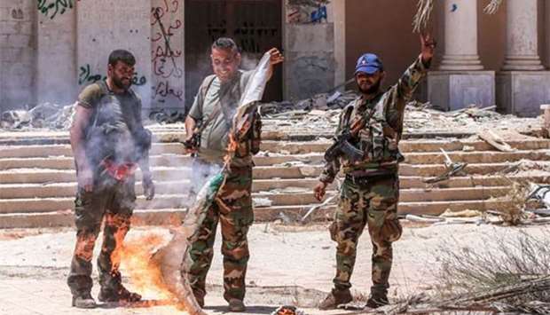 Syrian government soldiers burn an opposition flag while flashing the victory sign at the Nassib border crossing with Jordan in Daraa on Saturday.