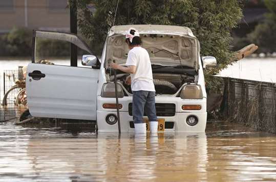 A man checks a car in a flooded area in Mabi town in Kurashiki, Okayama Prefecture.