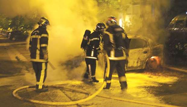 Firefighters douse flames from a burning car in the Le Breil neighbourhood of Nantes before dawn yesterday.