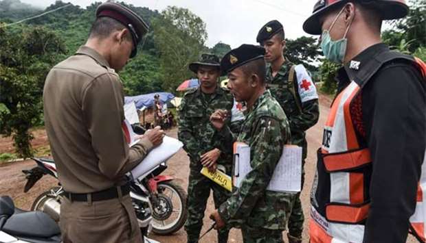 A Thai policeman speaks with a Thai soldier at the Tham Luang cave area as operations continue in Khun Nam Nang Non Forest Park in the Mae Sai district of Chiang Rai province on Sunday.