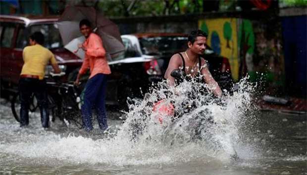 A man rides a motorcycle through a waterlogged street during heavy rains in Mumbai.