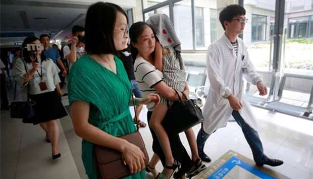 A girl, with her head covered with a towel who survived a Thailand tourist boat disaster, arriving to receive medical treatment at a hospital in Haining in China's eastern Zhejiang province.
