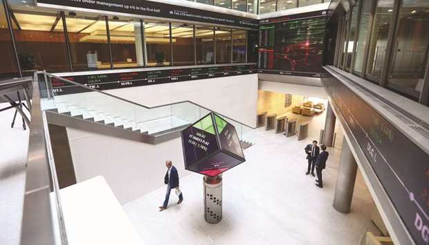 Visitors walk past an illuminated rotating cube displaying share price information at the London Stock Exchange. The FTSE 100 closed 0.08% down at 7,530.69 points yesterday.