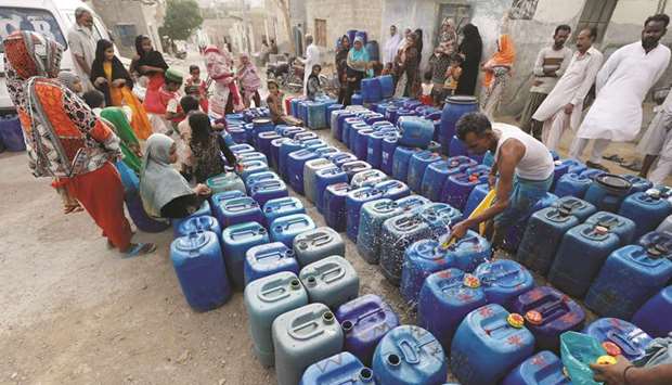Residents gather to fill empty containers at a free water distribution point in a low-income neighbourhood on the outskirts of Karachi.