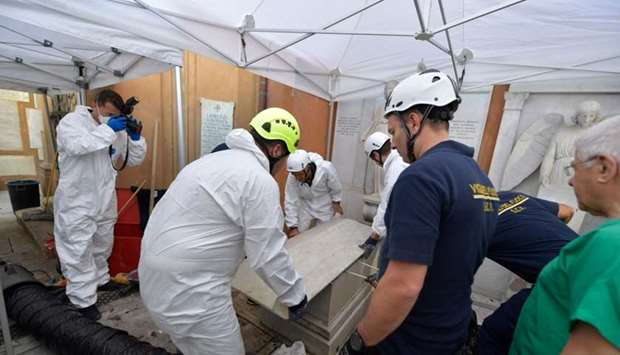Forensics (L) and firefighters (R) opening of one of two tombs within the Vatican's grounds in the Teutonic Cemetery