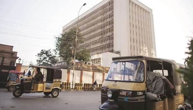 Auto rickshaws travel past the State Bank of Pakistan building in Karachi.