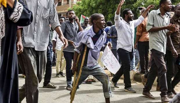 A Sudanese protester walking with a crutch joins others in a march during a mass demonstration against the country's ruling generals in the capital Khartoum's twin city of Omdurman