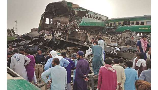 Local residents gather around the wreckage at the site where two trains collided in Rahim Yar Khan.
