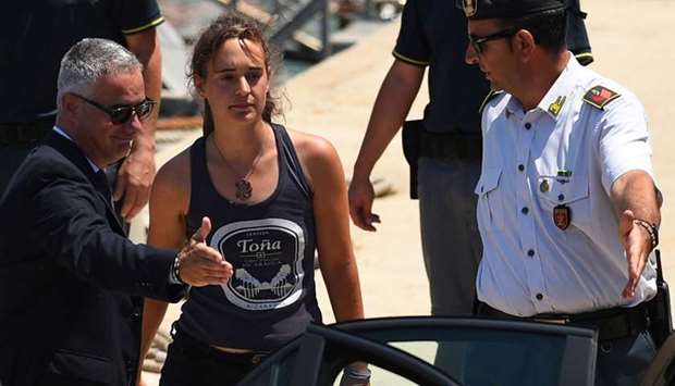 Carola Rackete, the 31-year-old Sea-Watch 3 captain, disembarks from a Finance police boat and is escorted to a car, in Porto Empedocle