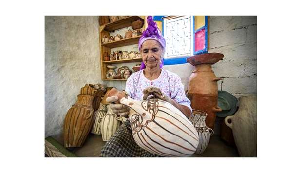 Moroccan potter Aicha Tabiz, also known as Mama Aicha, holds one of her works near the village of Ourtzagh in the foothills of the Rif mountains in Morocco.