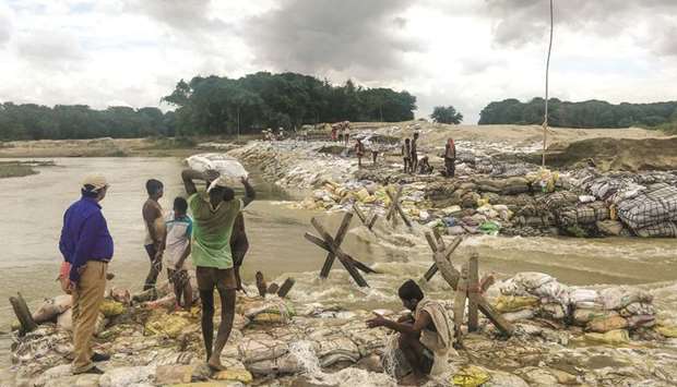 Locals gather concrete fragments and heavy bags wrapped in nets to build a dam as floodwaters flow into Muzaffarpur, Bihar.