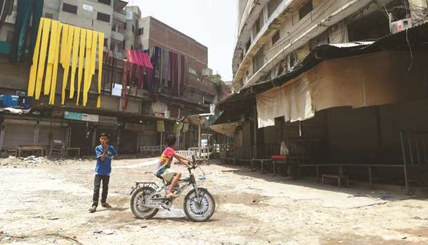 Children play in front of a shuttered market during a traders countrywide strike against the prices hike in Lahore yesterday.