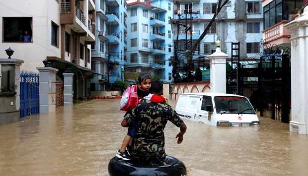 A member of Nepalese army carrying a child walks along the flooded colony in Kathmandu, Nepal July 12
