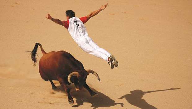 A recortador jumps over a bull during a contest in a bullring at the San Fermin festival in Pamplona.