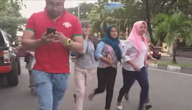 A man checks his phone as people run after an earthquake in Ternate, North Maluku, Indonesia yesterday in this still image taken from social media video.